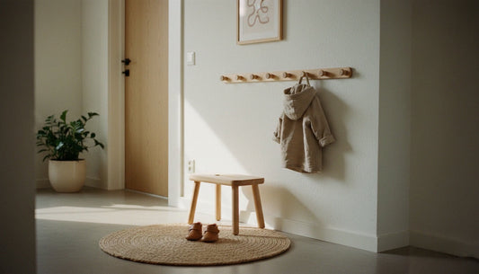 Ein minimalistisch eingerichteter Flur nach Montessori mit einem kleinen Holzhocker und niedrigen Kleiderhaken für Kinder.