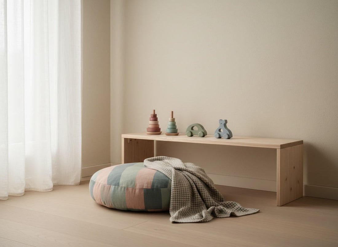 Aufgeräumtes Kinderzimmer im skandinavischen Stil mit einer niedrigen Holzbank, ausgewählten Holzspielzeugen in Pastelltönen und einem gemütlichen Bodenkissen nach dem Montessori-Prinzip von Jefani-Kids.